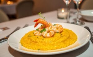 Prato de risoto de camarão cremoso, com camarões decorativos e toque de salsinha.