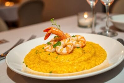 Prato de risoto de camarão cremoso, com camarões decorativos e toque de salsinha.